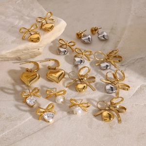 Close-up of assorted stainless steel bow and heart earrings with pearls and zircons