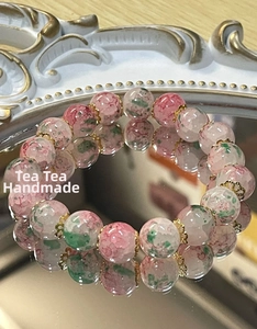 Macro shot of pink and green cracked glass beads with golden floral metal spacers