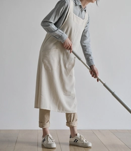 Detail of beige linen apron with neck strap and large front pocket in natural light