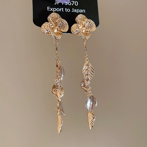 Close-up of elegant gold tassel earrings featuring detailed flower and leaf motifs