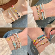 Detail of colorful beaded bracelets with pearls and charms stacked on model's wrist