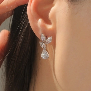 Elegant leaf and teardrop stud earrings with marquise stones on a model