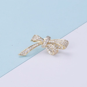 Macro detail of high-shine gold bow brooch with micro-set zircon and sparkling crystals