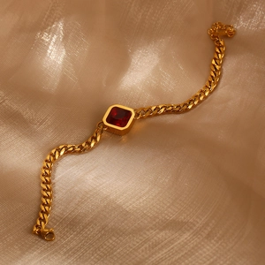 Makro-Detail des goldenen Panzerarmbands mit quadratischem rotem Zirkon auf Seide