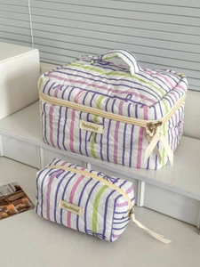 Set of two striped quilted cosmetic bags with purple bow patterns and ribbon zipper pulls