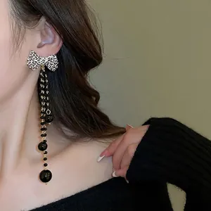 Leopard print bow earrings with long black beaded tassels on a fashion model