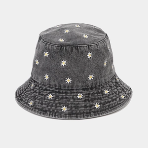 Close-up of small white daisy embroidery on dark grey denim cotton fisherman hat