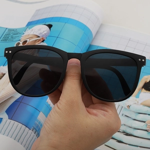 Close-up of black oversized oval sunglasses with silver rivet detail and matte finish