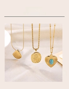 Detailed view of three vintage gold necklaces with shell and heart pendants on fabric
