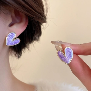 Close-up of purple marble effect heart stud earring with gold-plated edges on model
