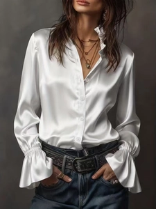 Close-up of elegant white satin shirt with ruffle cuffs and stand collar details