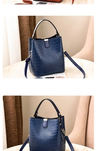 Detail of dark blue crocodile texture bucket bag with gold hardware and top handle