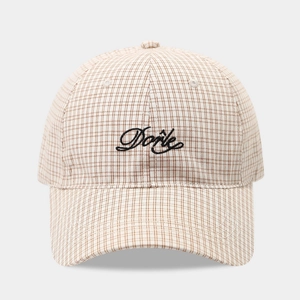 Close-up of beige plaid baseball cap featuring black cursive Done letter embroidery