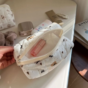 Detailed view of cream quilted cotton makeup bag with bear and bow patterns and zipper