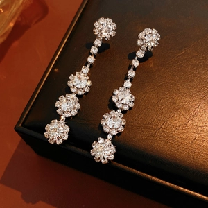Close-up of silver flower tassel earrings with rhinestones on a brown leather display box