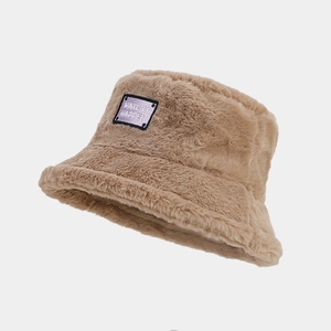 Détail d'un bob en peluche camel avec texture en fausse fourrure douce et écusson carré