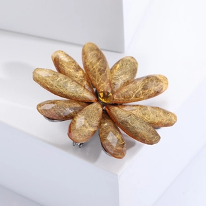 Detail of amber acrylic flower brooch with golden silk texture and yellow rhinestone