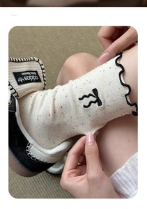 Detail of cream calf socks with black wavy cuffs and embroidered letter K detail