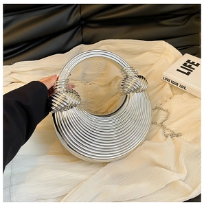 Gros plan du sac demi-lune argenté avec poignée anneau et chaîne en métal sur tissu blanc