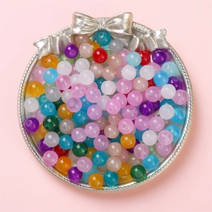 Mix of colorful round jelly glass beads for DIY jewelry making displayed on a silver plate