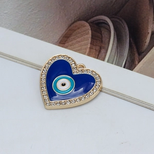 Close-up of heart-shaped evil eye pendant with blue enamel and gold-plated rhinestone border