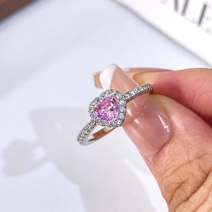 Close-up of a pink heart-shaped gemstone ring with halo diamond setting on silver band