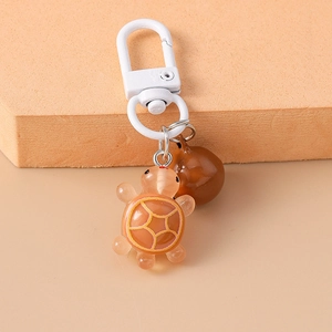 Detailed macro shot of orange resin turtle keychain with brown charm on beige stand