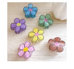 Detailed view of colorful flower hair claws in six candy tones on a wooden surface