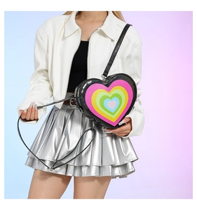 Close-up of heart-shaped crossbody bag with rainbow layers paired with a silver skirt