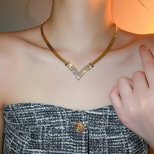 Close-up of gold-plated V-shaped necklace with sparkling diamonds on flat snake chain