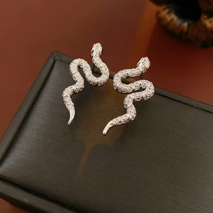 Détail macro de boucles d'oreilles serpent en argent avec zircons sur socle noir