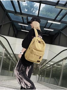 Yellow canvas backpack worn by a model on stairs, showing modern casual style and texture