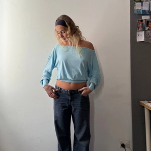 Detail of light blue one-shoulder long sleeve top showing slim fit and soft fabric