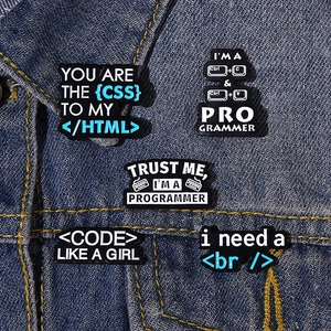 Detail of creative programmer enamel pins with coding icons on a blue denim jacket