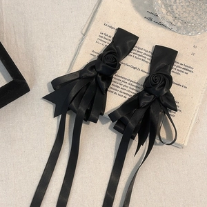 Detail of black satin rose hair clips with long ribbons on vintage French paper