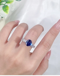 Detailed view of an oval blue gemstone ring in s925 silver on a model's finger