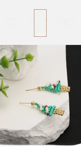 Macro shot of handmade Christmas tree earrings with natural pearls on white stone