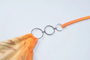 Detail view of orange gradient print fabric with silver metal connecting rings