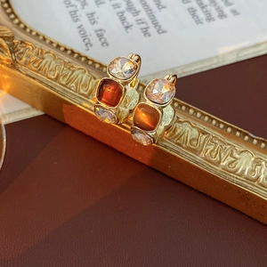 Close-up of vintage gold earrings with crystal and amber stones on a classic book