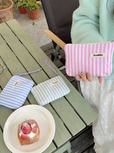 Three striped fabric cosmetic pouches for makeup storage in pink, blue, and green colors