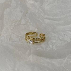 Elegant gold plated lace ring with square diamond center on white textured background