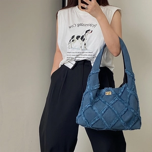 Detailed close-up of blue denim tote bag with textured diamond pattern and gold twist lock