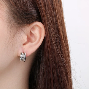 Close-up of a silver double-circle stainless steel earring worn by a model