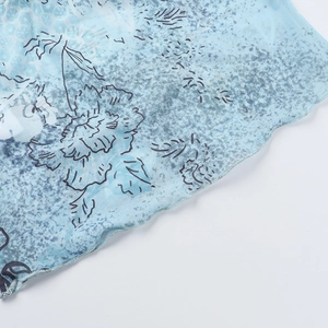 Nahaufnahme von blauem Mesh-Stoff mit Blumenmuster und Rüschenrand an einem Sommertop