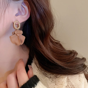Close-up of elegant gold metal hoop earrings with matte petal drops on a model