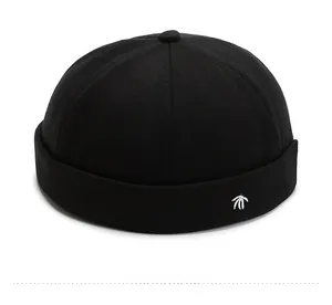 Detail of white coconut tree embroidery on a black cotton docker cap with brimless design