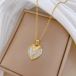 Luxurious gold heart necklace with white cat eye stone and diamonds on soft fabric
