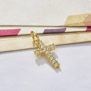 Gold cross pendant with clear cubic zirconia stones in a professional studio shot