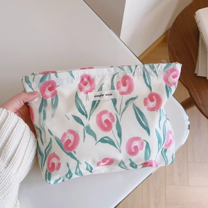 Détail de la trousse à maquillage en coton floral avec étiquette et texture toile