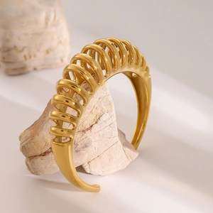 Macro shot of 18k gold plated stainless steel spiral open cuff bracelet on stone